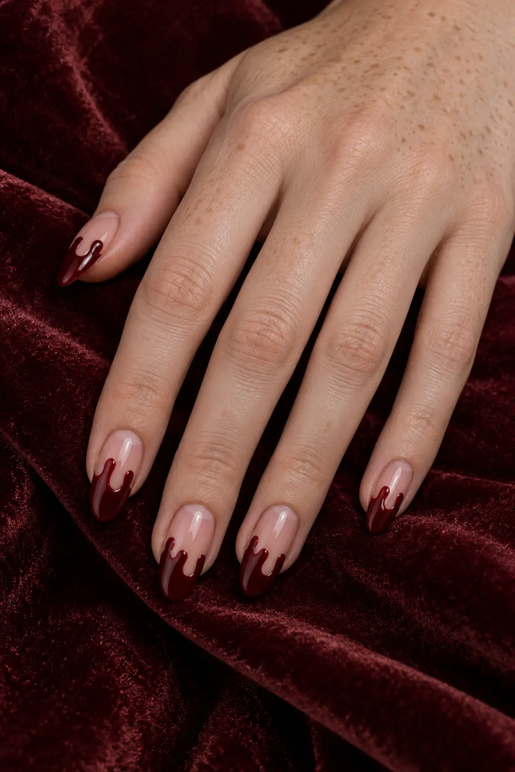 Sheer nude nails with glossy burgundy blood drip tips