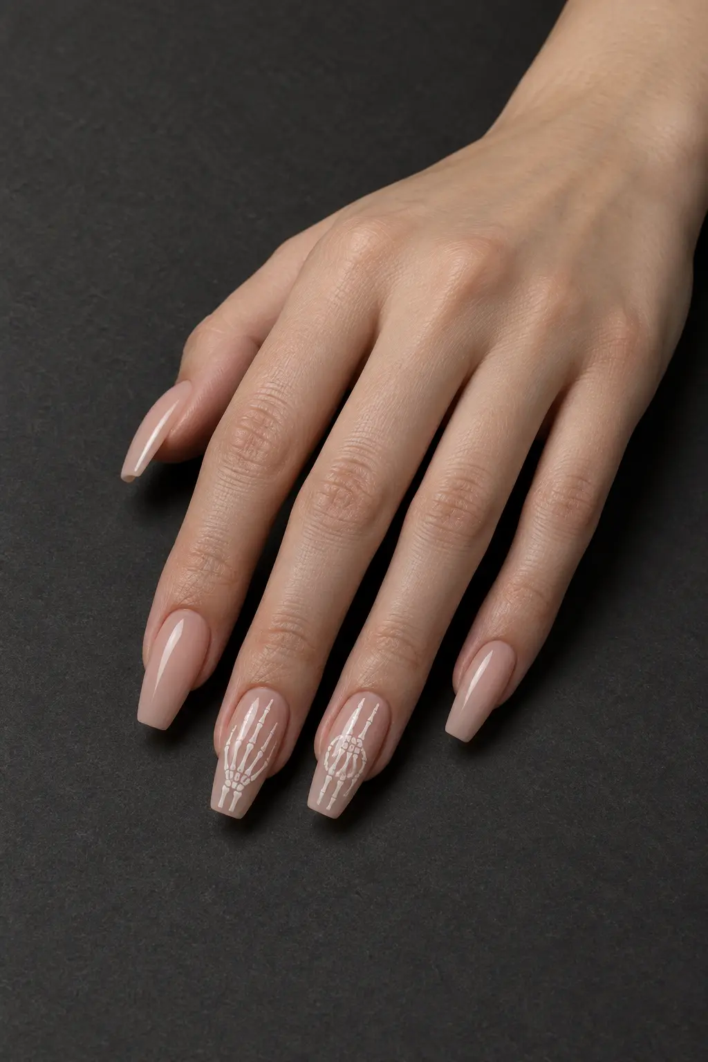 Sheer nude nails with delicate white skeleton hand accents