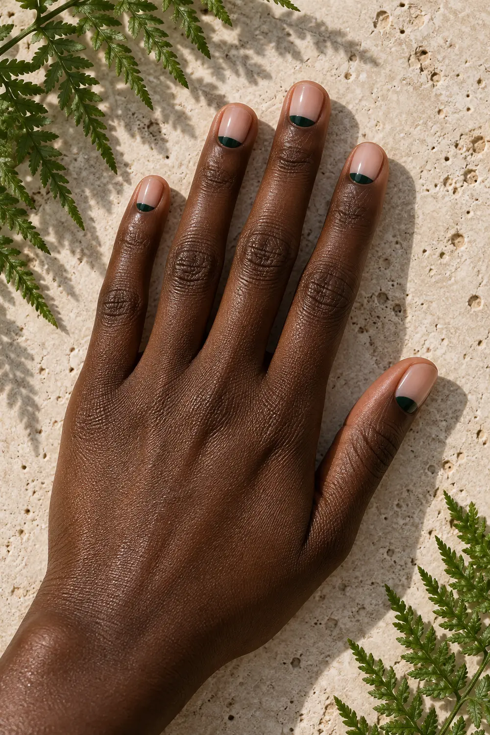 Nude nails with forest green half moons at the cuticles