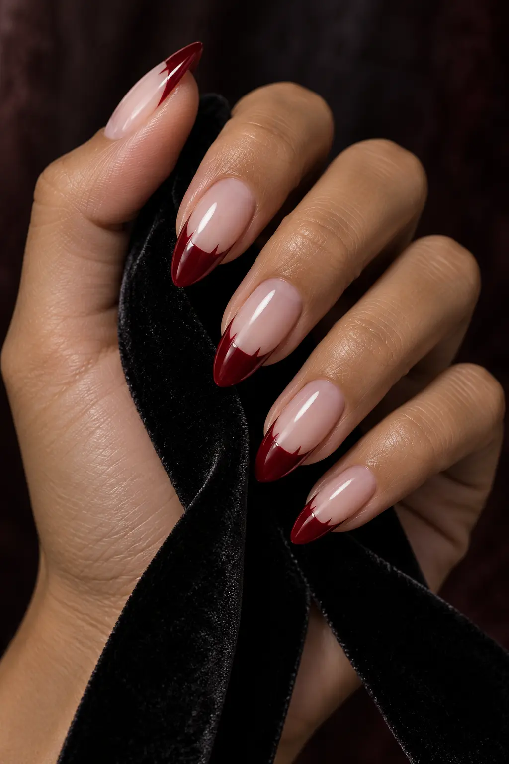 Sheer nude almond nails with deep red vampire French tips