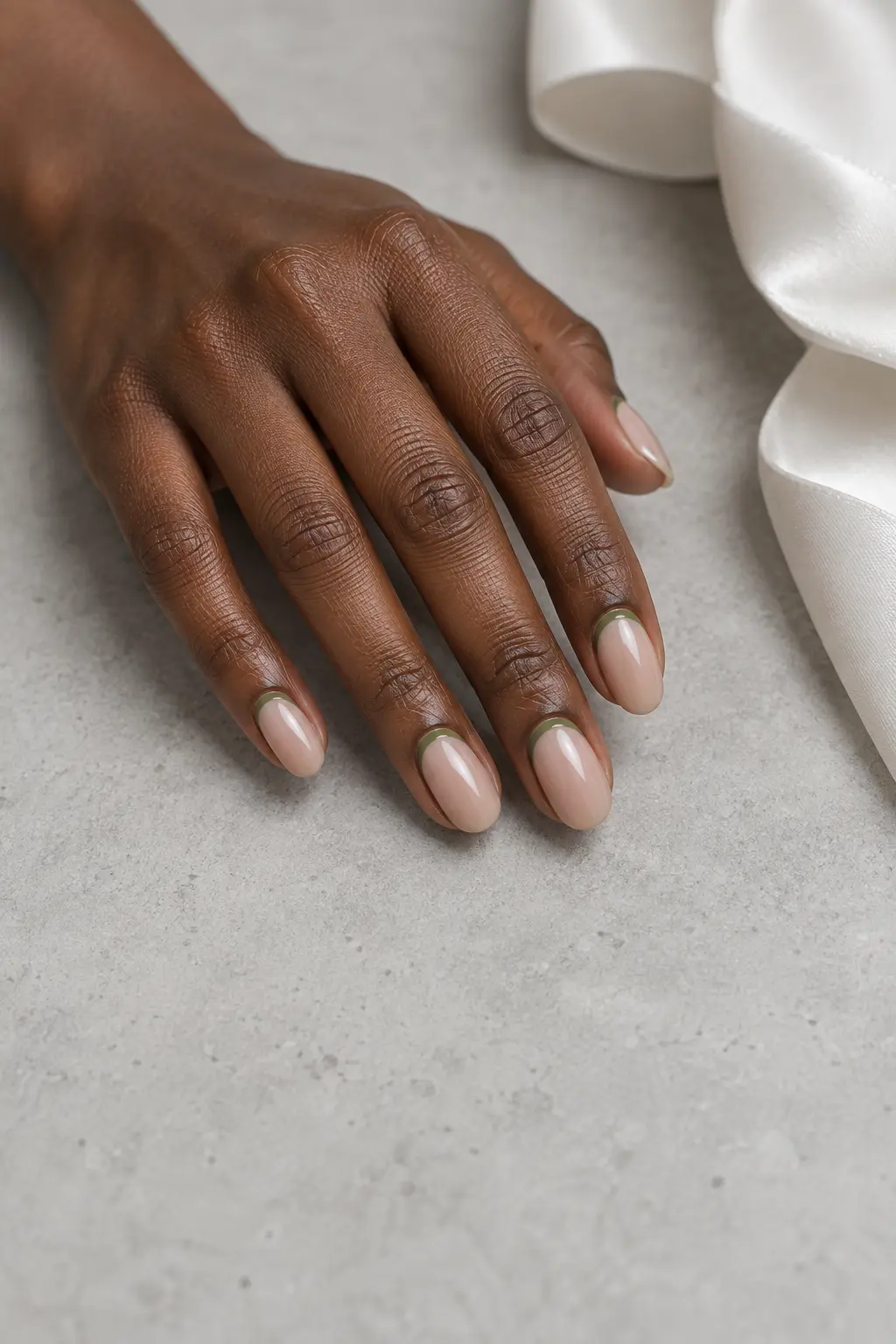 Sheer nude nails with slim olive green reverse French curves