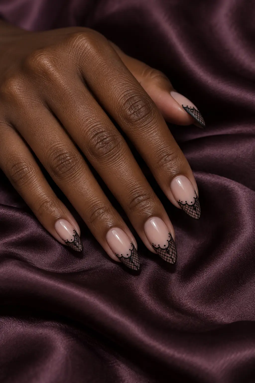 Sheer nude almond nails with delicate black lace tips