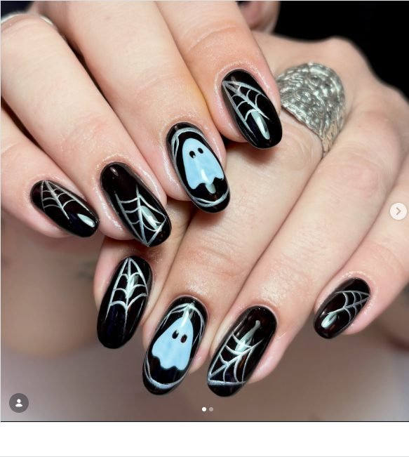 Glossy black nails with silver spider webs and pale blue ghost accent nails