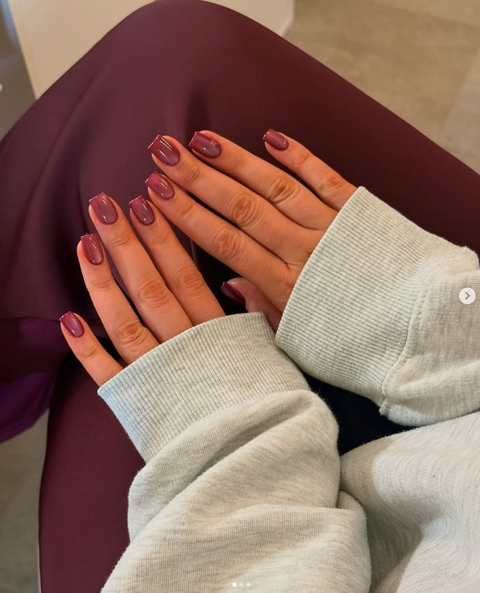 Short square nails in burgundy with a soft cat-eye shimmer