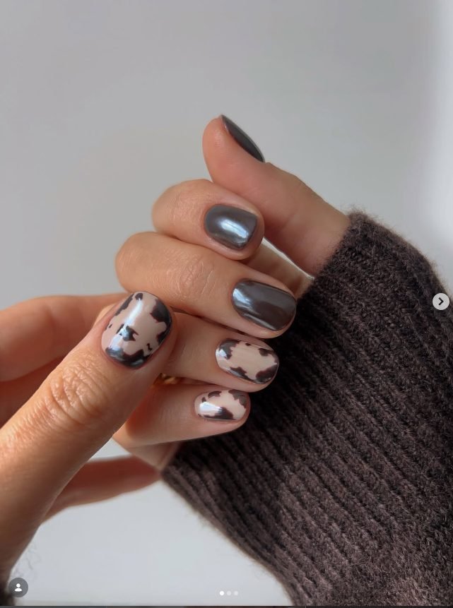 Short rounded nails in chocolate brown chrome with nude and brown cow print accents