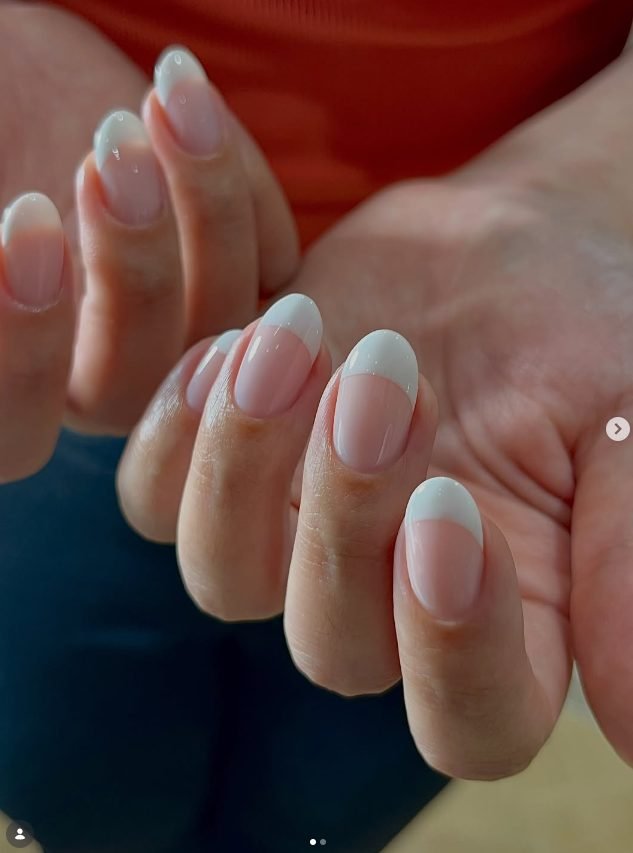 Oval nails with a sheer pink base and deep soft white 90s style French tips