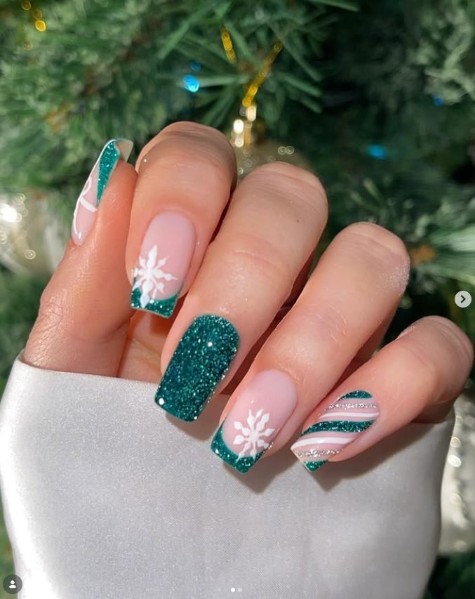 Square nails with emerald glitter French tips, white snowflakes, a full glitter nail and candy cane stripes