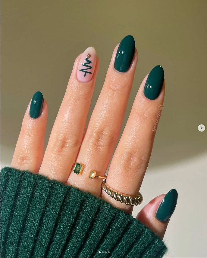 Glossy forest green almond nails with a nude accent nail showing a green zigzag Christmas tree