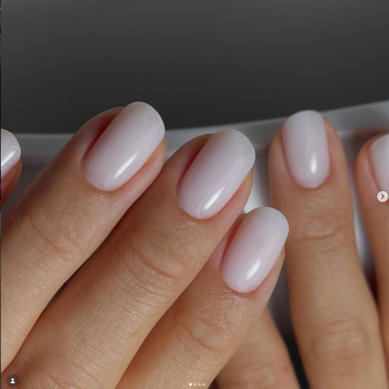 Short rounded nails in a smooth milky lilac white gel with a glossy finish