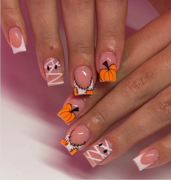 Short square nails with white French tips, a mummy nail, orange pumpkin tips and stitched patchwork tips