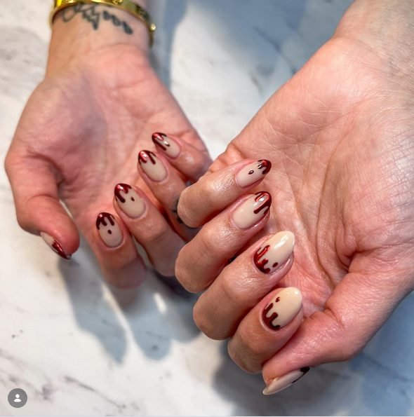 Nude nails with shiny red chrome drips running down from the tips