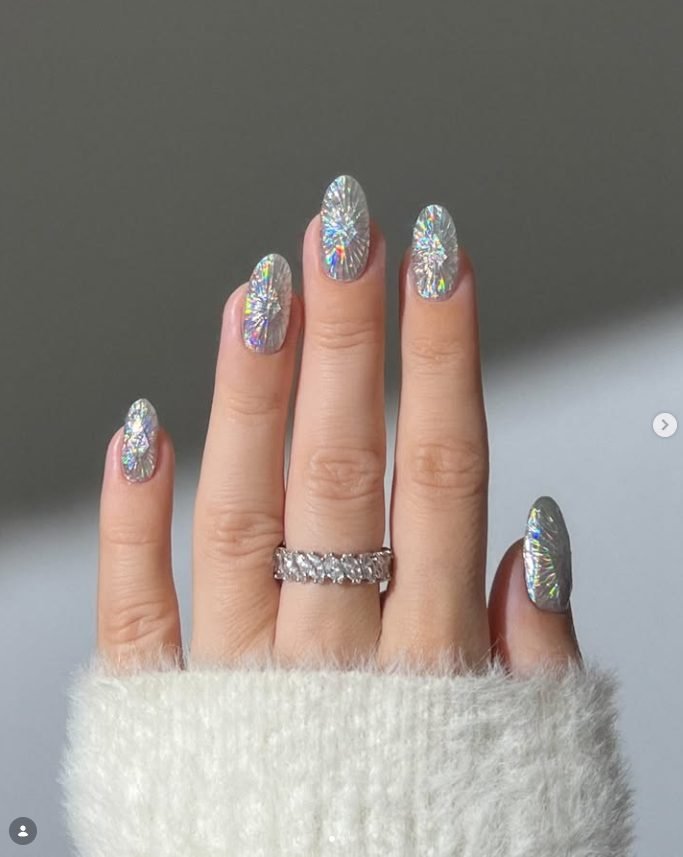Oval nails covered in silver holographic foil that looks like shattered crystal