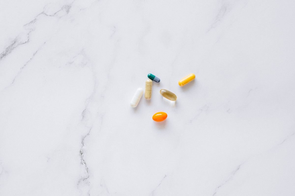 Assorted vitamin and supplement pills on a white marble surface