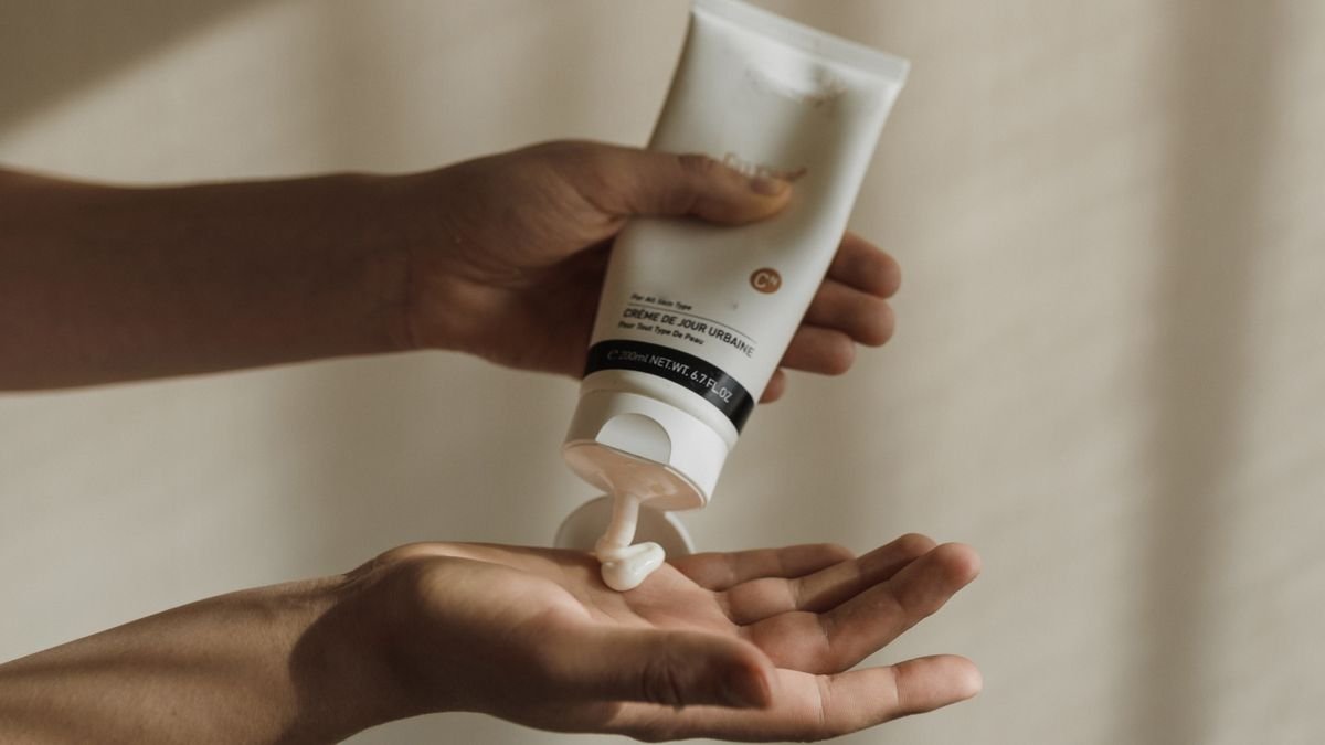 Woman squeezing hand cream onto her hand as part of a nail and skin care routine